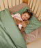 Toddler cuddling a teddy lying on top of a ergoPouch Organic Toddler Pillow Case Willow