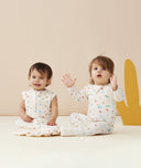 Smiling infants wearing  ergoPouch Long Sleeve Romper 0.2 TOG Desert Bloom and  Sleep Sack 0.2 TOG Desert Bloom