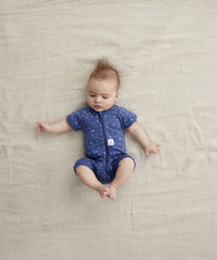 Infant lying with knees up in a ergoPouch Short Sleeve Romper 0.2 TOG Night Sky