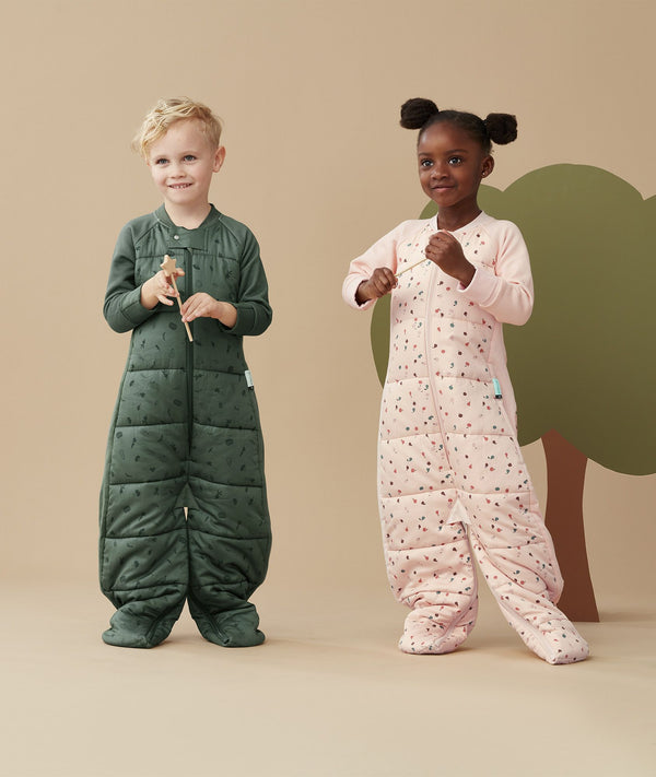 Two children standing in an ergoPouch Sleep Suit Sack 2.5 TOG Cute Fruit and Veggie Patch, a warm sleeping bag that converts to a sleeping bag with legs