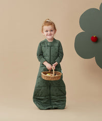 Child standing in an ergoPouch Sleep Suit Sack 2.5 TOG Veggie Patch, a warm sleeping bag that converts to a sleeping bag with legs