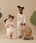Two children standing in an ergoPouch Sleep Suit Sack 3.5 TOG Cute Fruit, a warm sleeping bag that converts to a sleeping bag with legs