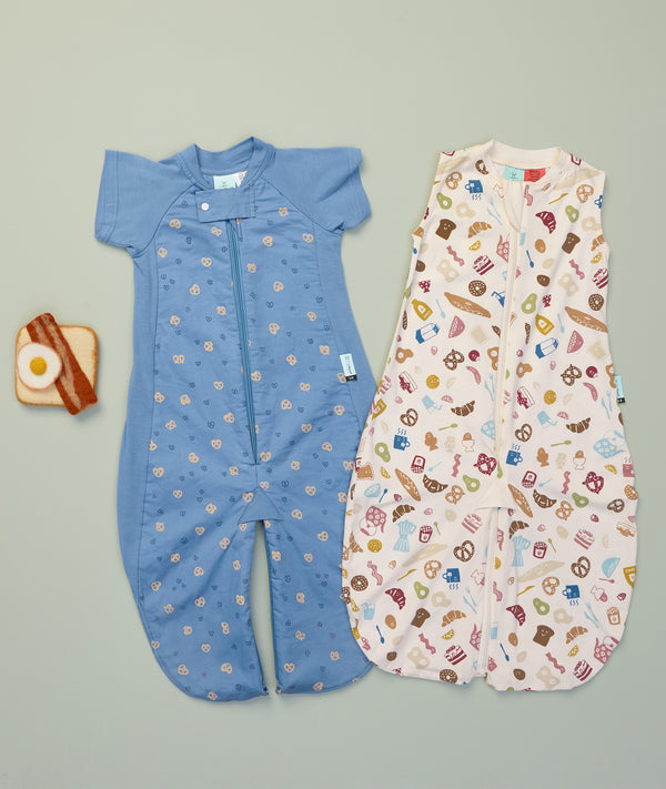 Flatlay of ergoPouch Jersey Sleep Suit Sack 0.2 TOG Bon Appetit and Sleep Suit Sack 1.0 TOG Petit Pretzel