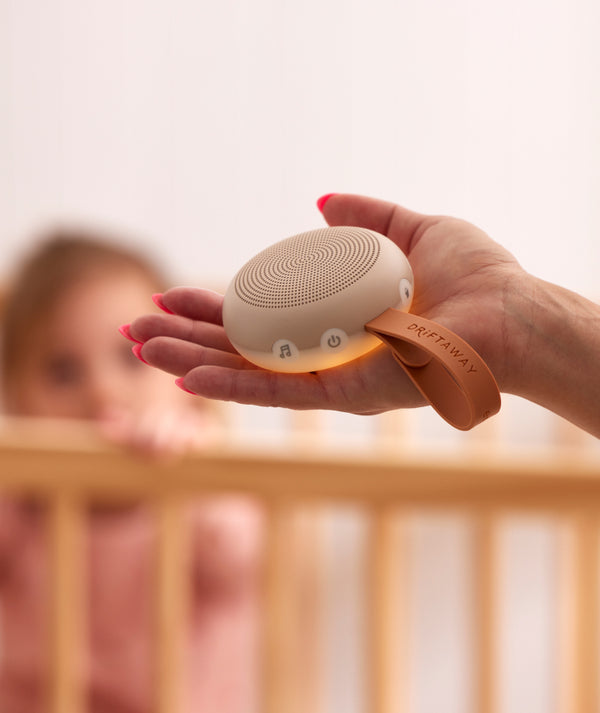 ergoPouch  White Noise Machine being held in a hand, featuring seven different soothing sounds