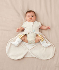 Baby wearing an ergoPouch Hip Harness Cocoon Swaddle Sack 0.2 TOG Oatmeal Marle with legs out