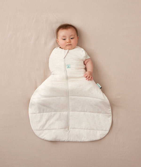 Baby wearing a ergoPouch Hip Harness Cocoon Swaddle Sack 3.5 TOG Oatmeal Marle, transitioning to arms out sleeping