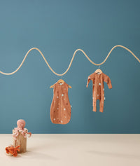 Hanging product shot of ergoPouch Cocoon Swaddle Sack 0.2 TOG and Long Sleeve Romper Sunny