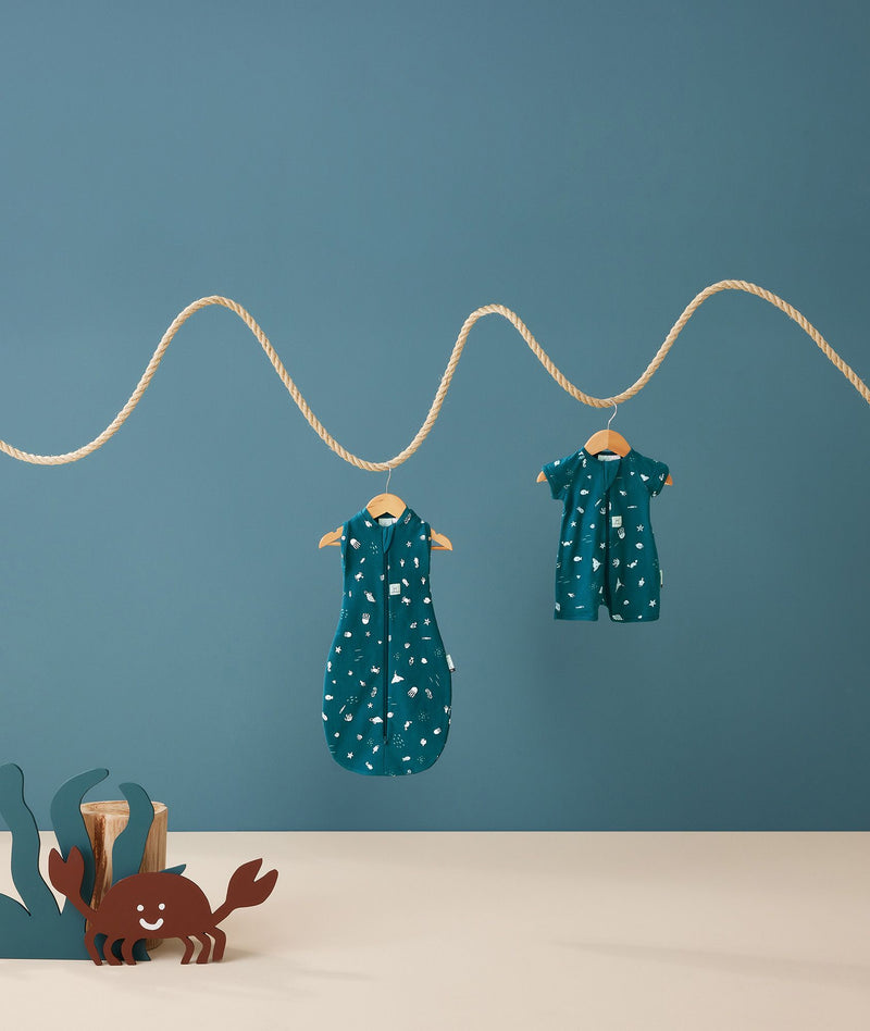 Product shots of ergoPouch Cocoon Swaddle Sack 0.2 TOG and Long Sleeve Romper in Ocean Blue