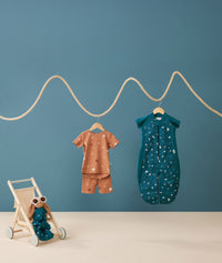 Flatlay of ergoPouch Short Sleeve Pajamas 0.2 TOG Sunny and Sleep Suit Sack 1.0 TOG Ocean Blue