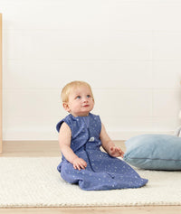Infant sitting wearing a light ergoPouch Sleep Sack 0.2 TOG Night Sky