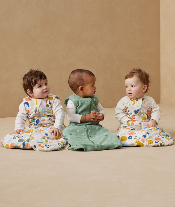 Three babies sitting in ergoPouch Sleep Sack 3.5 TOG Sleeved Fruit Salad and Sweet Orchard
