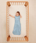 Smiling infant in a crib wearing ergoPouch Sleeping Sack 1.0 TOG Dragonflies