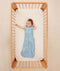 Smiling infant in a crib wearing ergoPouch Sleeping Sack 1.0 TOG Dragonflies