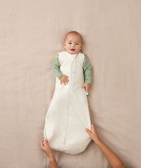Infant lying in a crib wearing an ergoPouch Sleeping Sack 0.2 TOG Oatmeal Marle perfect for the summer