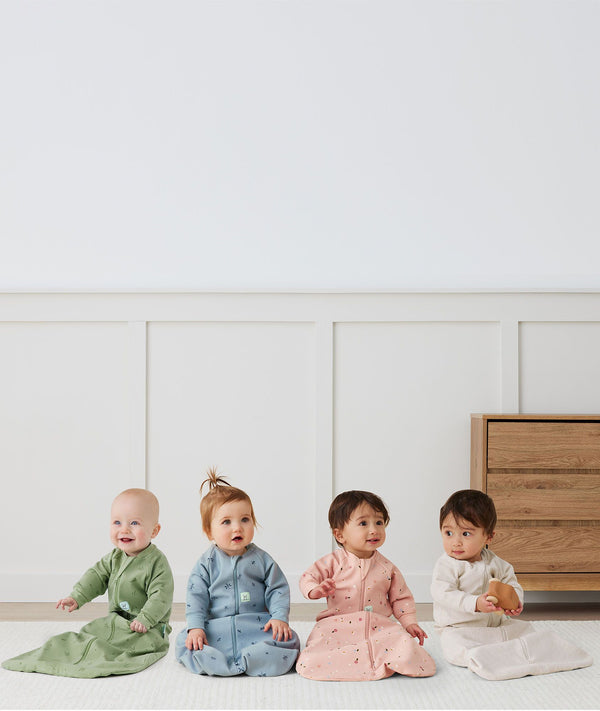 Four infants sitting in ergoPouch Sleep Sack 1.0 TOG Sleeved Daisies, Dragonflies, Willow and Oatmeal Marle