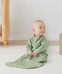 Newborn sitting, wearing an ergoPouch Sleeping Sack 1.0 TOG Sleeved Willow