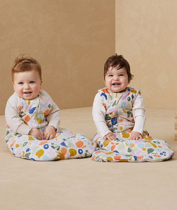 Two babies sitting in ergoPouch Sleep Sack 3.5 TOG Sleeved Fruit Salad
