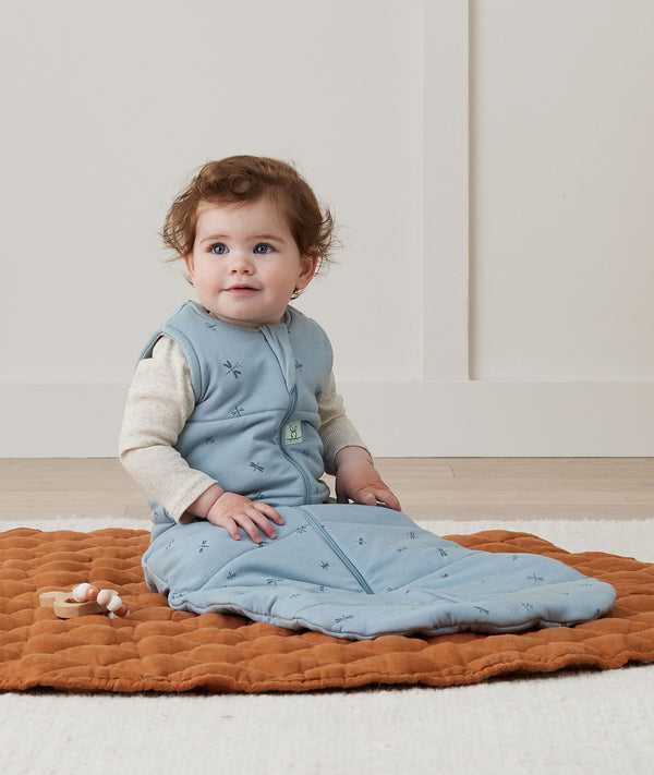 Newborn sitting, wearing an ergoPouch Sleeping Sack 2.5 TOG Dragonflies