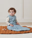 Newborn sitting, wearing an ergoPouch Sleeping Sack 2.5 TOG Dragonflies