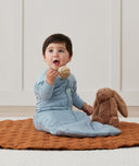 Newborn sitting, wearing an ergoPouch Sleeping Sack 3.5 TOG Dragonflies