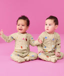 Two infants sitting on the floor wearing ergoPouch Long Sleeve Romper 0.2 TOG in Birthday Blobs 