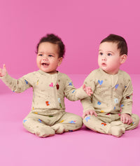 Two infants sitting on the floor wearing ergoPouch Long Sleeve Romper 0.2 TOG in Birthday Blobs 