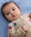 Close up of newborn baby looking into the camera wearing ergoPouch Long Sleeve Romper 0.2 TOG in Birthday Blobs
