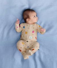 Newborn baby lying on it's back with feet in the air in ergoPouch Long Sleeve Romper 0.2 TOG in Birthday Blobs