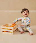 Baby sitting in ergoPouch Long Sleeve Romper 1.0 TOG Fruit Salad