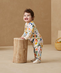 Infant standing, wearing an ergoPouch Long Sleeve Romper 1.0 TOG Fruit Salad
