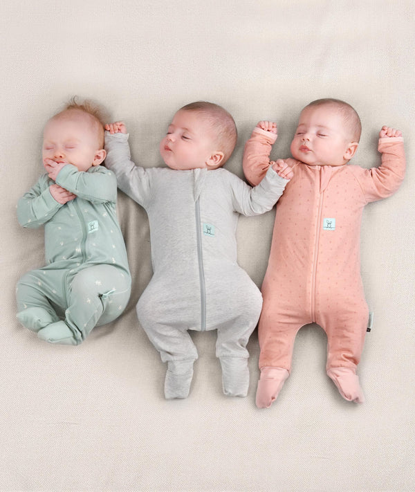 Three newborns wearing an ergoPouch Long Sleeve Romper 0.2 TOG in different colours