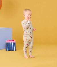 Toddler standing with fingers in his mouth wearing ergoPouch Long Sleeve Pajamas 0.2 TOG in Birthday Blobs 