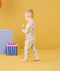 Toddler walking away with candy in his hand wearing ergoPouch Long Sleeve Pajamas 0.2 TOG in Birthday Blobs 