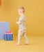 Toddler walking away with candy in his hand wearing ergoPouch Long Sleeve Pajamas 0.2 TOG in Birthday Blobs 