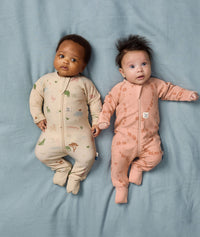 Two babies lying side by side wearing ergoPouch Long Sleeve Rompers 1.0 TOG in Savannah and Elephant Parade