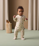 Infant standing in ergoPouch Long Sleeve Romper 1.0 TOG Savannah with foot cuffs folded over to retain warmth and protect skin.