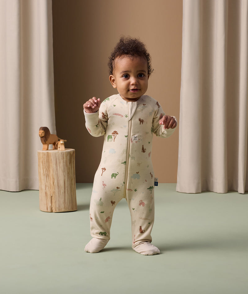 Infant standing in ergoPouch Long Sleeve Romper 1.0 TOG Savannah with foot cuffs folded over to retain warmth and protect skin.
