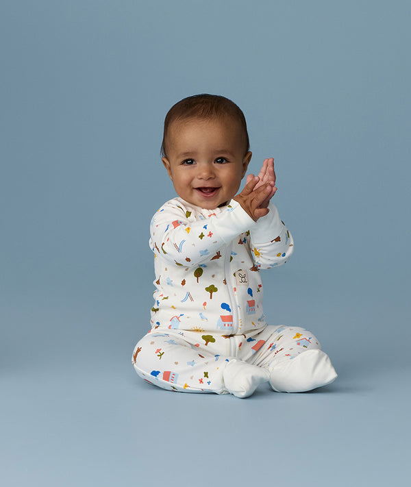 Happy infant sitting in an ergoPouch Long Sleeve Romper 1.0 TOG Daydream