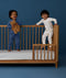 Two children standing in a crib wearing ergoPouch Long Sleeve Romper 1.0 TOG Daydream and Starbeam