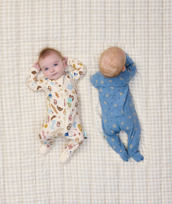 Two newborn babies lying down in ergoPouch Long Sleeve Romper 1.0 TOG in Petit Pretzel and Bon Appetit