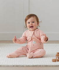 Infant sitting with thumbs out wearing ergoPouch Long Sleeve Romper 1.0 TOG Daisies