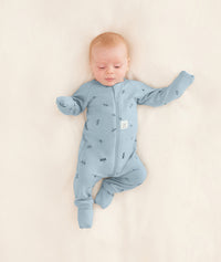 A baby is dressed in an ergoPouch Long Sleeve Romper with its foot and hand cuffs folded over for extra warmth and protection.