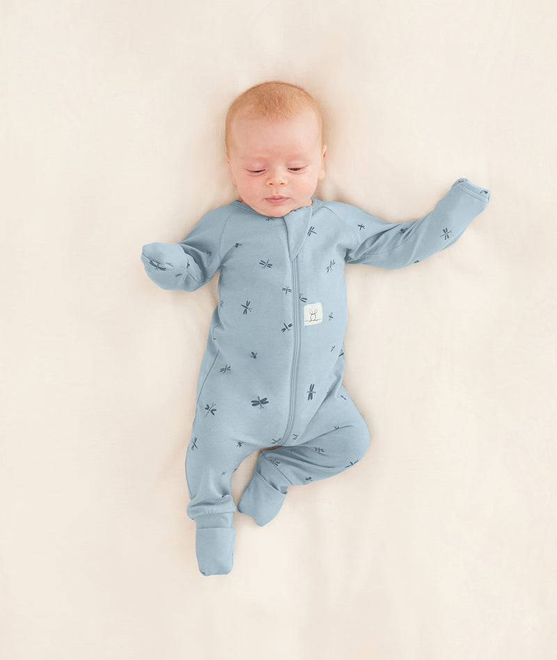 A baby is dressed in an ergoPouch Long Sleeve Romper with its foot and hand cuffs folded over for extra warmth and protection.