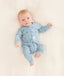 A baby is lying in a neutral color blanket wearing an ergoPouch Long Sleeve Romper in Dragonflies.