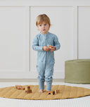 Toddler standing, wearing an ergoPouch Long Sleeve Romper 1.0 TOG Dragonflies