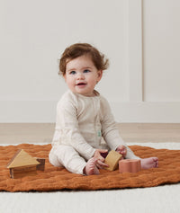 Baby sitting and playing with wooden blocks, wearing ergoPouch Long Sleeve Romper 1.0 TOG Oatmeal Marle and Daisies