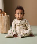 Infant sitting on the floor in ergoPouch Long Sleeve Romper 1.0 TOG Savannah with foot cuffs folded over.