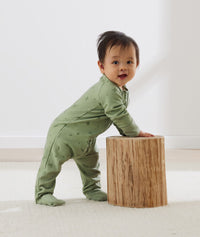 Infant standing, wearing an ergoPouch Long Sleeve Romper 1.0 TOG Willow