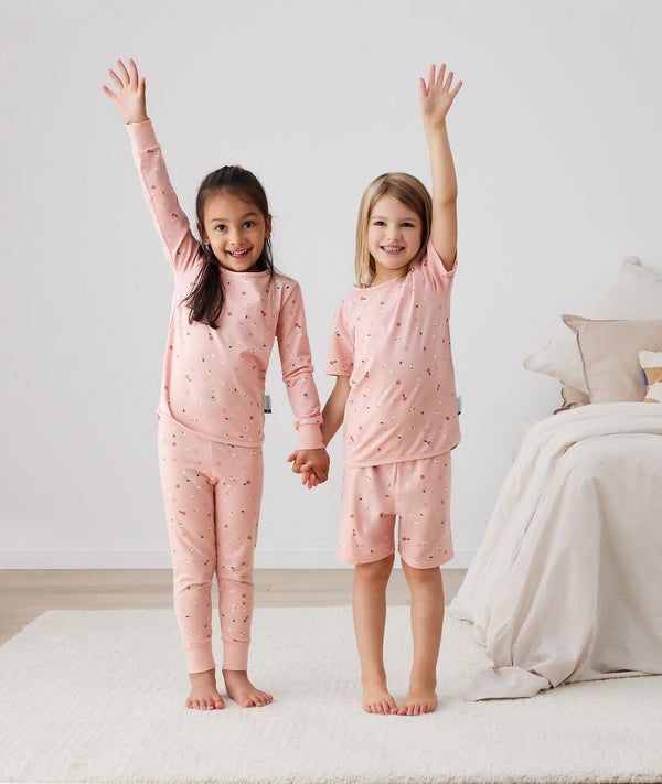 Two toddler holding hands in ergoPouch Short Sleeve Pajamas 0.2 TOG Daisies, perfect for the summer
