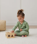 Toddler playing with wooden toy, wearing an ergoPouch Long Sleeve Pajamas 1.0 TOG Willow